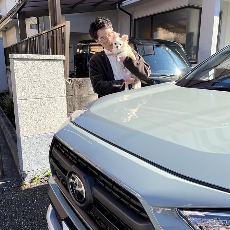 車の横で犬を抱き抱える社員